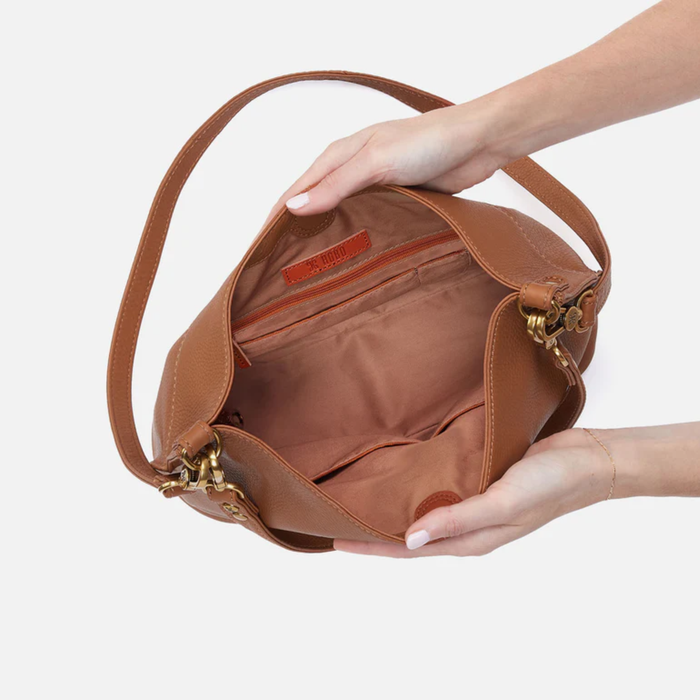 HOBO Pier Shoulder Bag in warm honey pebbled leather, showcasing a stylish design and spacious interior.