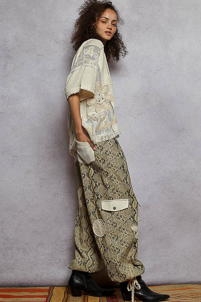 Pol Clothing pleat detail floral patchwork cargo pants with multiple pockets and colorful floral pattern.