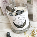 Lunastry Protection from Assholes Candle with a humorous label, featuring a tall white candle in a glass holder.