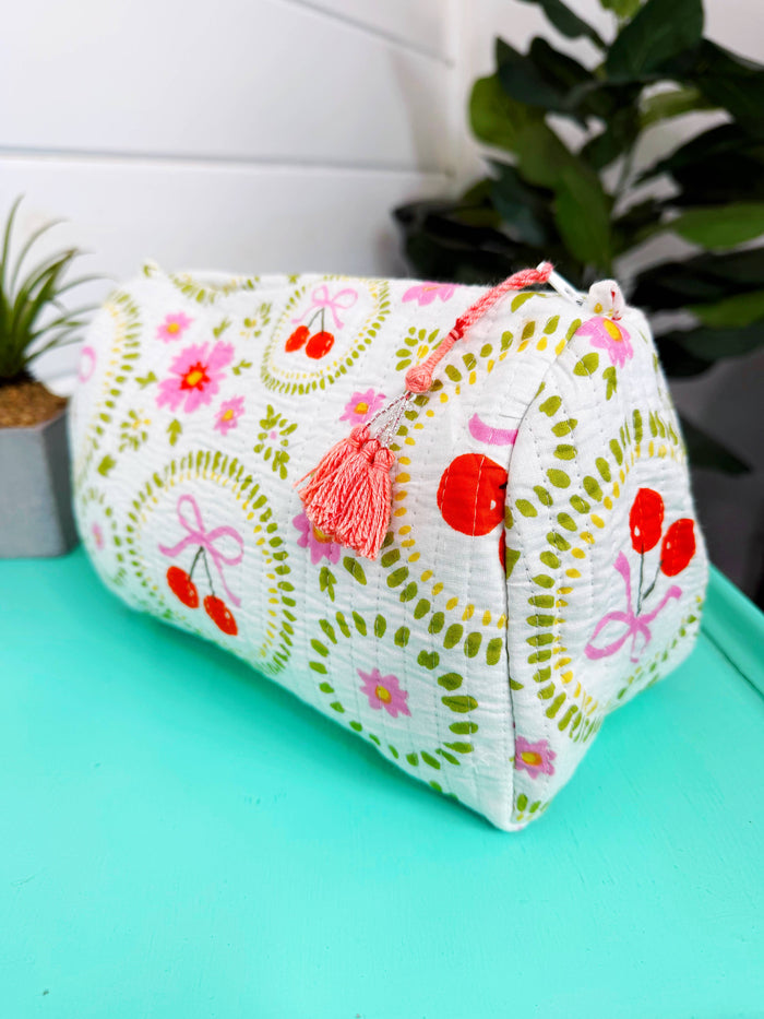 White quilted Folklore Couture makeup pouch with cherry and bow design, featuring a compact cosmetics bag for storing beauty essentials.