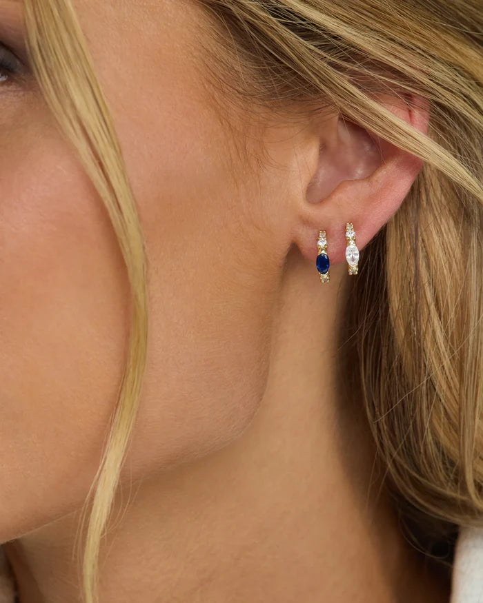 Gold The Maven Huggies earrings by Melinda Maria featuring a sleek, minimalist hoop design with a polished finish.