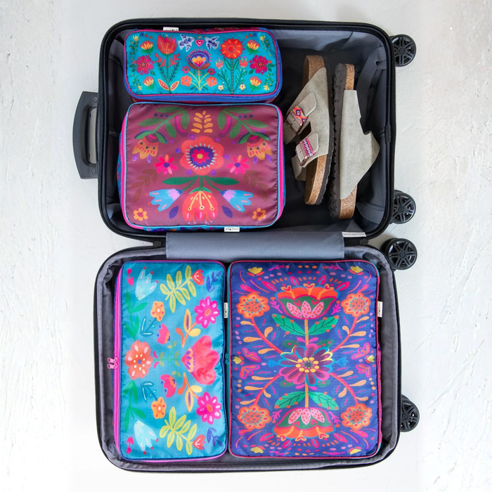 Set of four Natural Life travel packing cubes with colorful folk flower patterns, ideal for organizing luggage.