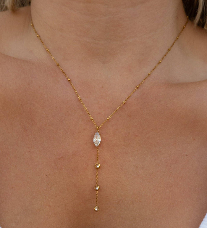 Gold necklace with a central gemstone on a person's neck